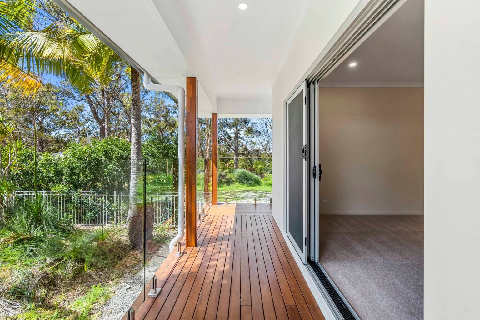 Covered timber deck with glass balustrade and bushland outlook at the Ney Road renovation, Capalaba