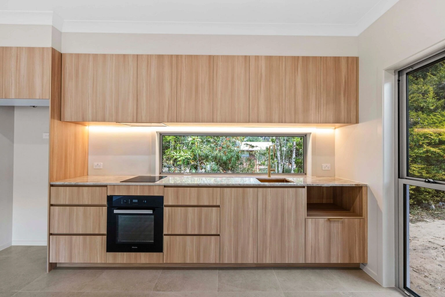 Kitchen with window splashback and gold tapware at the Ney Road renovation, Capalaba