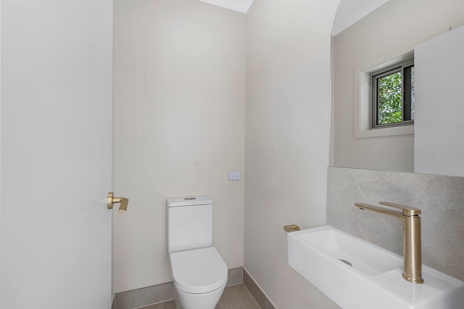 Powder room with wall-hung basin and gold tapware at the Ney Road renovation, Capalaba